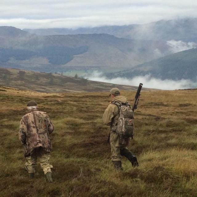 Deer stalkers walking across an upland landscape